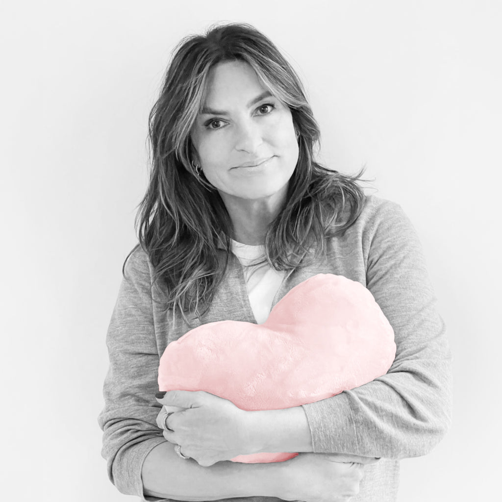 This is an image showing SVU actor and Joyful Heart Foundation founder Mariska Hargitay holding a pink colored heart-shaped pillow.