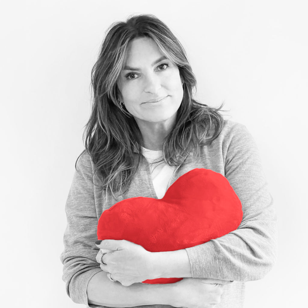 This is an image showing SVU actor and Joyful Heart Foundation founder Mariska Hargitay holding a red colored heart-shaped pillow.