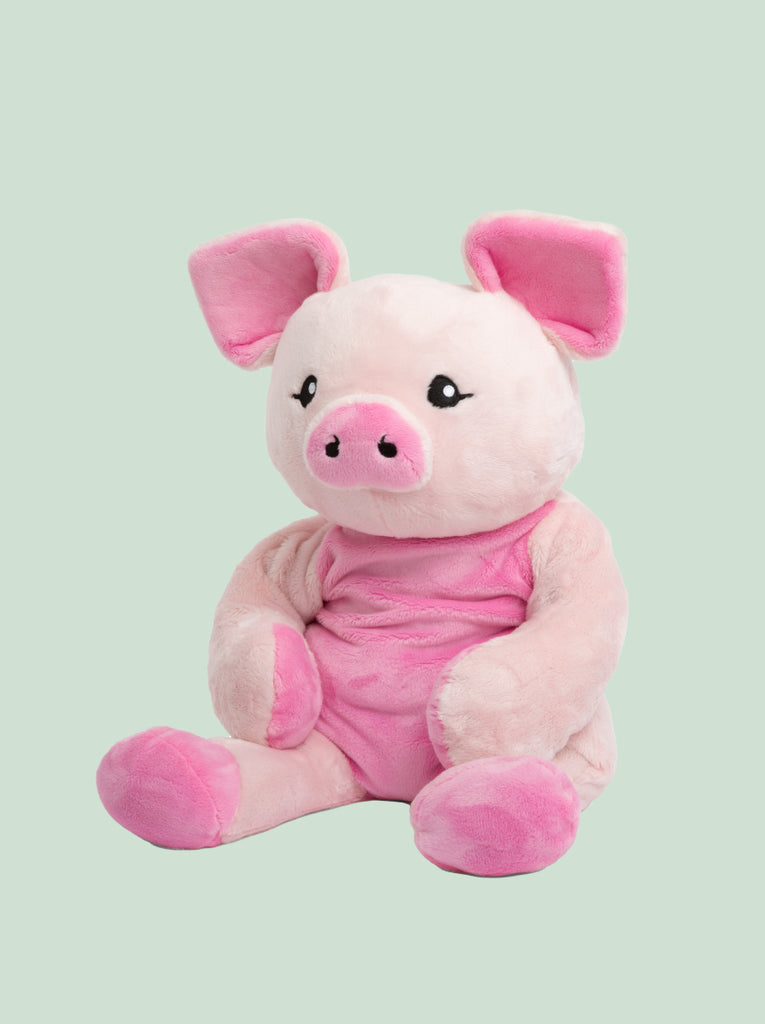 This photo shows Harper The Pig Hugimal, a pink piggie stuffed animal, sitting, turned slightly away from the camera but not quite profile view, surrounded by a mint green background.