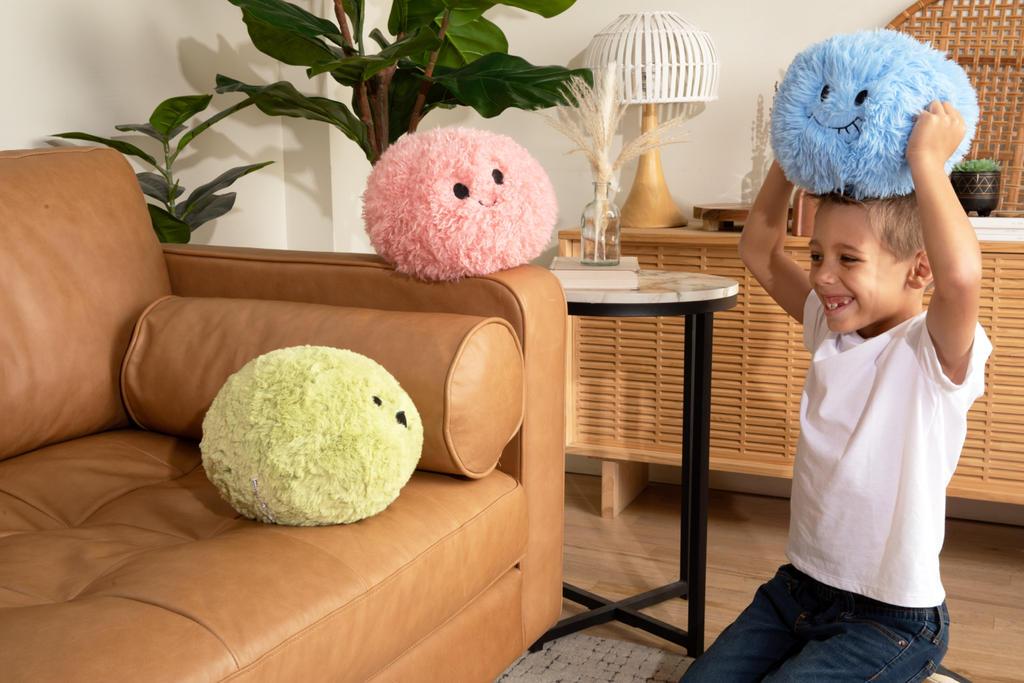 This photo shows a little by playing with all three of the Hug Ball: The Blue one he's holding on his head, and he's smiling at the Green Hug Ball on the tan couch, as the Pink Hug Ball looks on