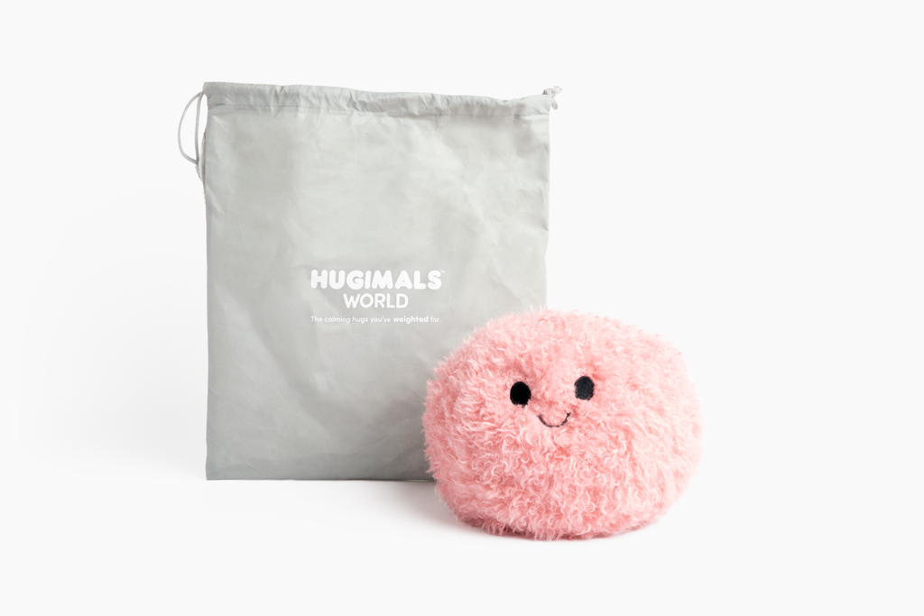 This photo shows the Pink Hug Ball with "Happy" expression on white background, with the Hugimals Branded light gray drawstring gift bag standing behind it.