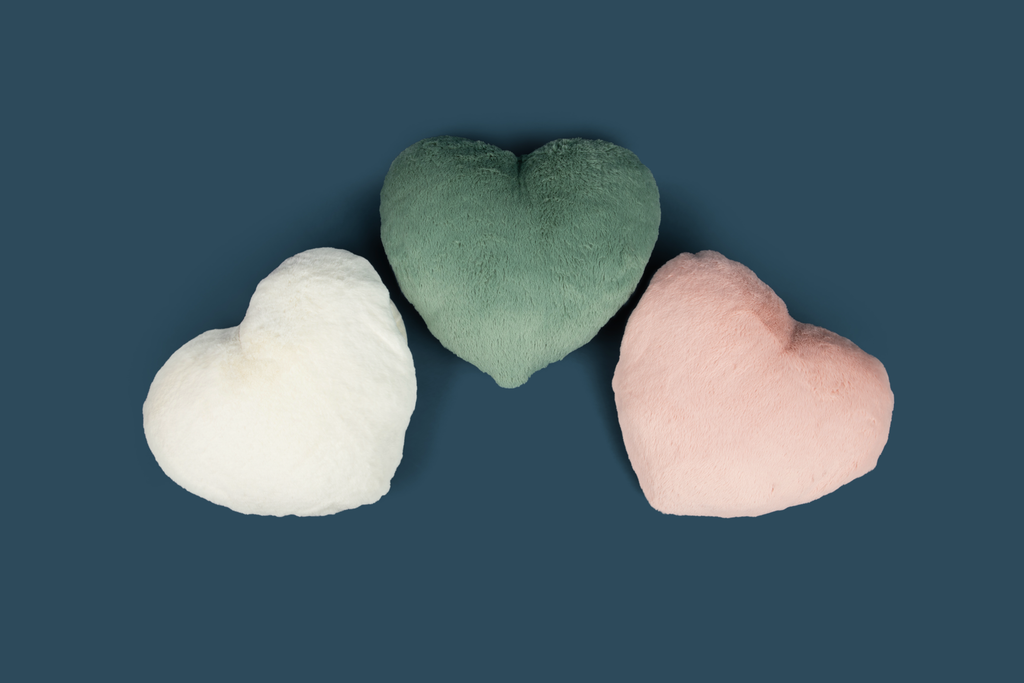 Image shows three Super Sized Heart to Hug Pillows arranged on a dark blue background: Ivory, Sage, Antique Rose